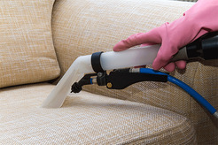 steam cleaning a cloth couch with a handheld accessory