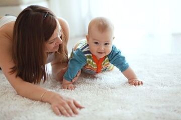 baby and mother playing on a freshly cleaned carpet happily
